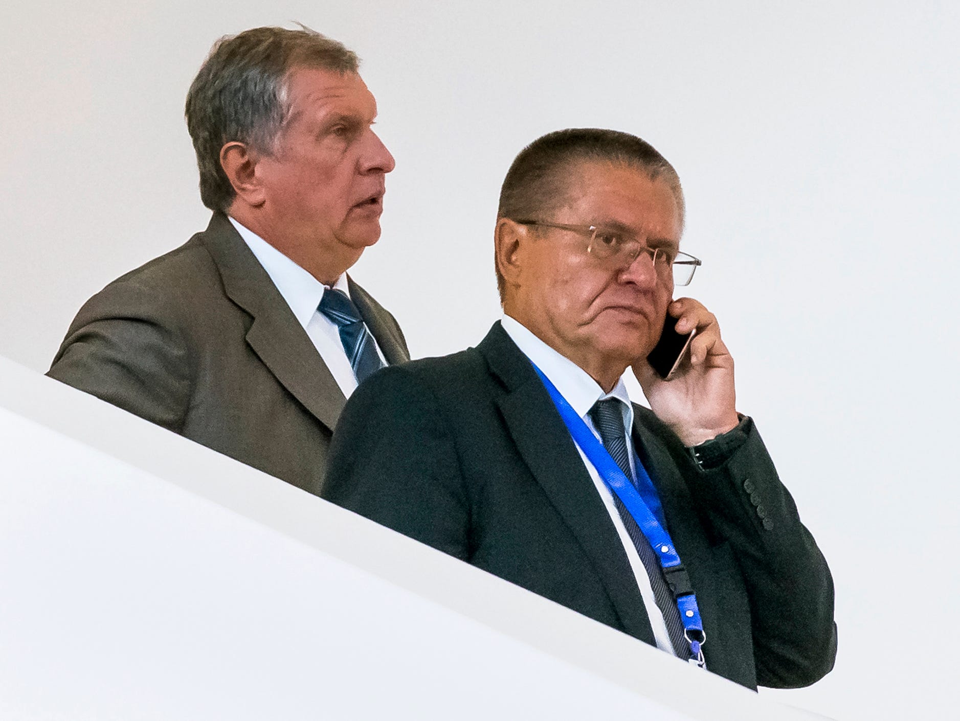 In this Monday, Aug. 8, 2016 photo, Economic Development Minister Alexei Ulyukayev, right, speaks on a mobile phone as he attends a meeting with Rosneft CEO Igor Sechin, left, in Baku, Azerbaijan.