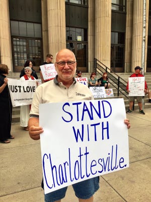 Retired minister Greg Smith holds a "stand with Charlottesville" sign at a Great Falls vigil Sunday.