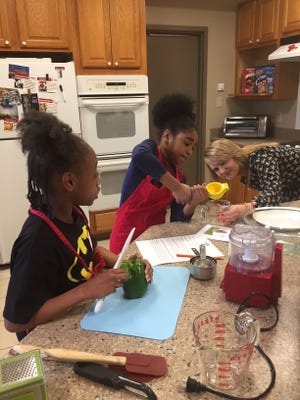 Trinity Edwards (from left),  Jus'ziyha Colvin Wicks and Ericha Grace,  Campbell’s volunteer coach, prepare hummus during a Zero Waste cooking class. The class is part of the Cooking Matters program administered at the Campbell Soup Company by the Food Bank of South Jersey.