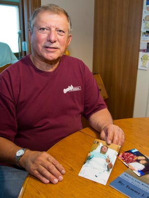 
Tom Bill shows a photo of himself during his battle with breast cancer at his home near Oxford. Dealing with a disease that has been dubbed a "women's fight," is difficult. "It's very emotional," he said. "It deals with something most people associate with women."
