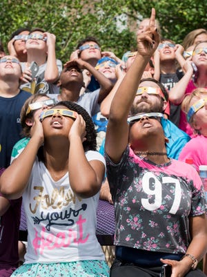 Anna Martin, bottom right, and fellow Brown-Barge Middle School students watch the solar eclipse at the West Florida Public Library on Spring Street in Pensacola on Monday, August 21, 2017.
