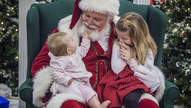 Caitlin Stuttle tests the integrity of Santa's beard while her sister, Evie, waits to tell him what she wants for Christmas at the Muncie Mall in this file photo.