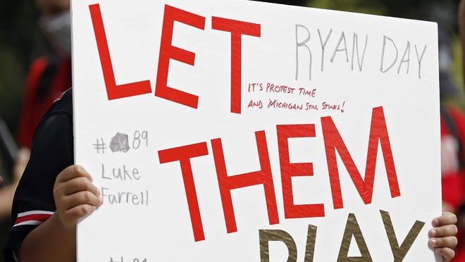 Graham Fleck, 11, of Grove City holds a sign during a rally organized by parents of Ohio State football players outside the rotunda of Ohio Stadium on Aug. 29.