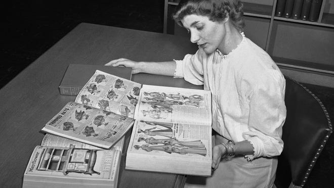 FILE - In an undated file photo, Ruth Parrington, librarian in the art department of the Chicago Public Library, studies early Sears Roebuck catalogs in the library's collection in Chicago. The catalog Parrington is holding features women's fashion from 1902. Sears has filed for Chapter 11 bankruptcy protection Monday, Oct. 15, 2018, buckling under its massive debt load and staggering losses. (AP Photo/File)