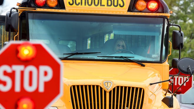 Viewed through the front windshield, bus driver Tracie Bosserman waits for students to be dismissed from school to bus them home from A.R. Ware Elementary on Tuesday, April 7, 2015. She has been driving buses for 14 years.