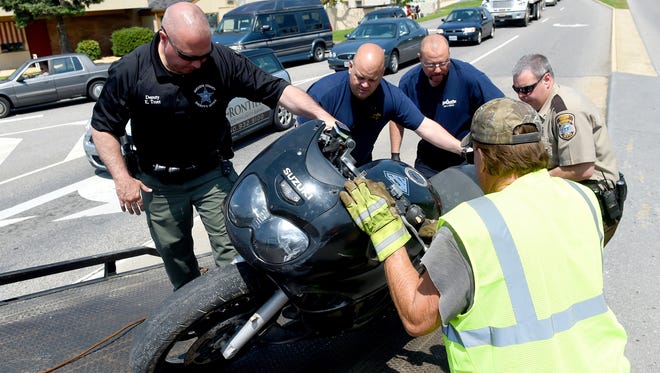 First responders work together to load a motorcycle onto a rollback tow truck following a single vehicle wreck involving the bike at Greenville Avenue and Statler Boulevard on Tuesday, April 21, 2015. Wanted on outstanding warrants, Richard Knight used the motorcycle in an attempt to elude law enforcement in a chase that began in the Buffalo Gap area and ended in Staunton. Knight lost control of the bike while going through the intersection. 