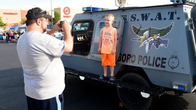 Dana Dixon, 7, of West Virginia stands proudly on the side of a Waynesboro Police SWAT vehicle as his grandfather, Ron Ward of Staunton, takes his photograph. They attend the 32nd National Night Out held at the Waynesboro Town Center on Tuesday, August 4, 2015.