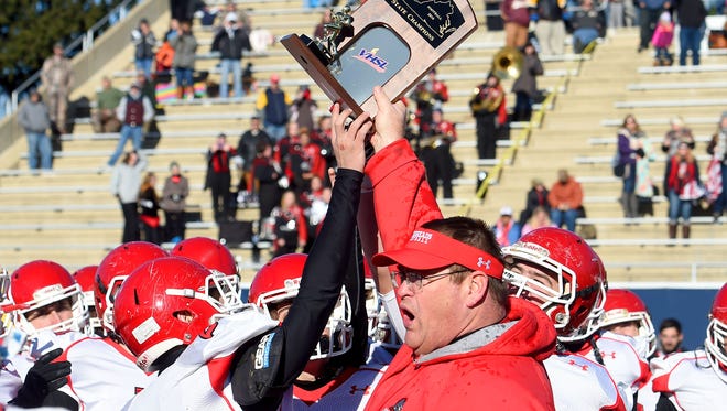 Riverheads' head coach Robert Casto holds high the Group 1A state championship trophy as he gives it to his players after defeating Sussex Central in a game played in Salem, 49-6. 