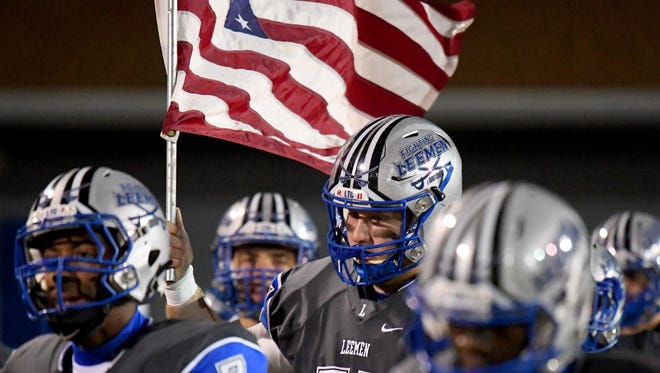 Robert E. Lee's Jack Coyner carries an American flag as the team takes the field for their Region 2B quarterfinal football game against George Mason played in Staunton on Friday, Nov. 10, 2017.