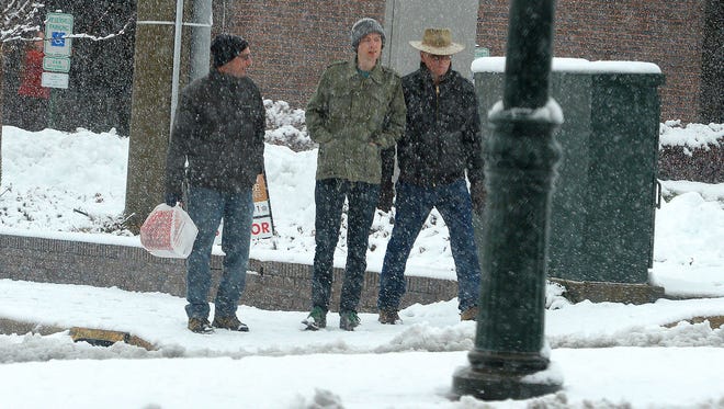 John Irwin of Los Angeles stands between Matt Getsey of Richmond and Larry Rayland of Staunton. They wait to cross North Augusta Street while walking around downtown Staunton in the falling snow on Wednesday, Nov. 26, 2014. "It's been four years since I last saw snow," said Irwin. 
