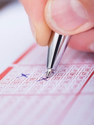 Person Marking Number On Lottery Ticket With Pen