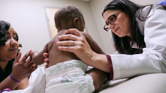 Dr. Mona Hanna-Attisha, pediatrician at Hurley Medical Center, talks with Flint resident Courtney Dudley while examining her daughter, Isabella Evans, during a wellness appointment at the Hurley Children's Center in downtown Flint in April 2016. 