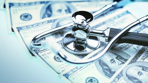 A stethoscope lying atop a fanned pile of hundred dollar bills.