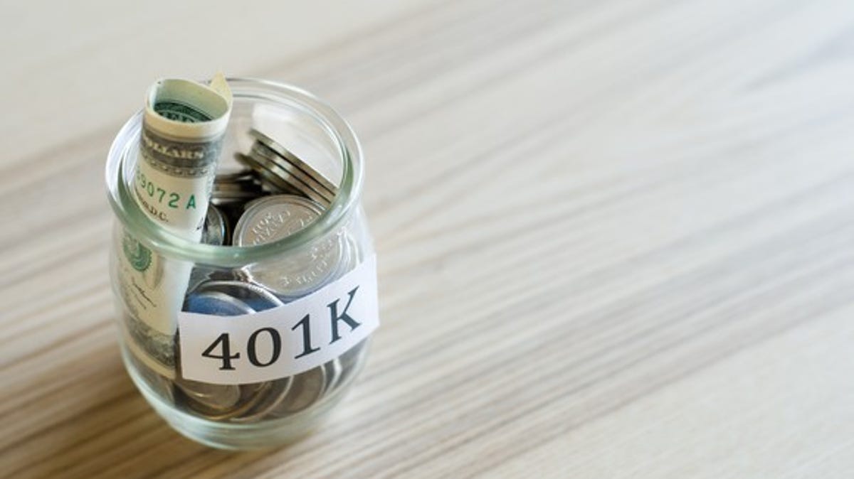 Glass jar labeled "401K" filled with rolled-up bills and coins.