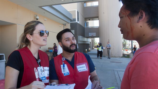 Emergency room nurses Taylor Fitzpatrick, left, and Matthew Lacanilao question a volunteer patient with simulated injuries outside Ventura County Medical Center in Ventura during a countywide training drill involving terrorist violence.
