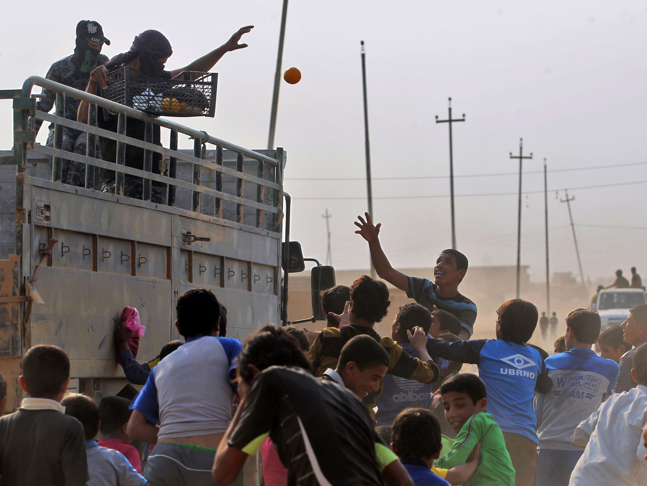 Iraqi forces distribute fruits to children in the village of al-Khuwayn, south of Mosul, after recapturing the village from Islamic State (ISIL) group jihadists on Oct. 23, 2016, in part of an ongoing operation to tighten the noose around Mosul and r
