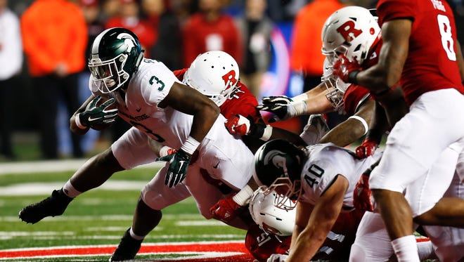 LJ Scott (3) of the Michigan State Spartans tries to break free from the line against the Rutgers Scarlet Knights. MSU won 40-7 to finish the regular season 9-3.