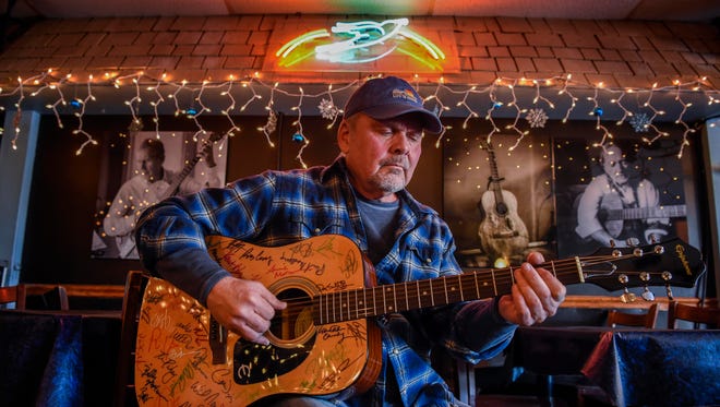 Songwriter Kent Blazy plays a guitar that has the signatures of the artists who are performing in January to benefit Alive Hospice at the Bluebird Cafe in Nashville on Jan. 18, 2018.