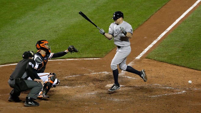 New York Yankees' Brett Gardner, right, spins around after being hit by a pitch with the bases loaded in front of Baltimore Orioles catcher Caleb Joseph and home plate umpire Chris Guccione in the eighth inning of a baseball game in Baltimore, Wednesday, May 4, 2016. Didi Gregorius walked in for a run on the play.