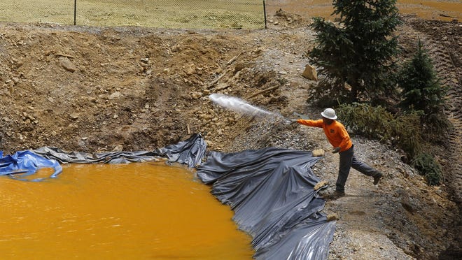 An employee with Environmental Restoration LLC tends to a temporary water treatment holding facility on Aug. 10, 2015, at the Gold King Mine north of Silverton, Colo.