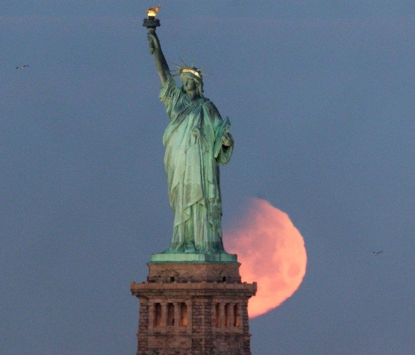 The moon sets behind the Statue of Liberty in New York on Jan. 31.