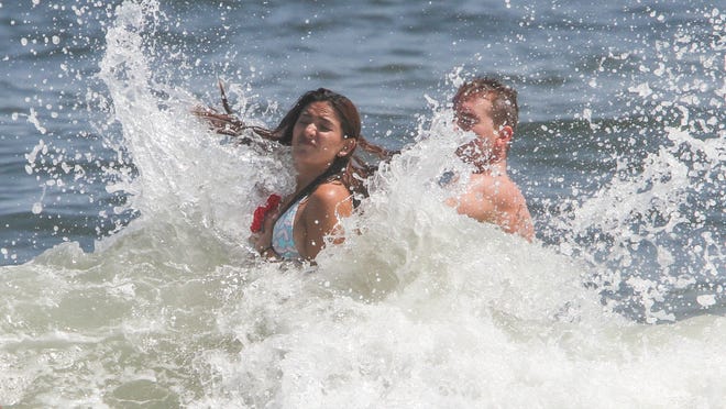 
Bathers get hit by a wave in Belmar Monday.

