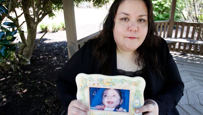 In this April 19 photo, Alyssa Pladl, holds a photo of her daughter, Katie, when she was an infant at a park in Richmond, Virginia. Alyssa is the ex-wife of Steven Pladl, who was charged with incest after he impregnated his biological daughter, Katie. Pladl killed the 7-month-old son he had with Katie, then killed Katie and her adoptive father in Connecticut and killed himself in New York.
