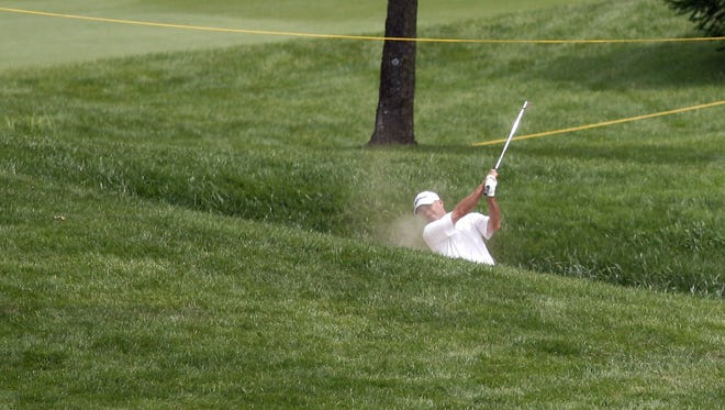 A golfer chips the golf ball out of the seventh hole sand trap.