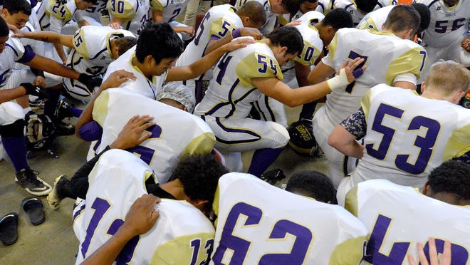 Hands touching fellow players, Waynesboro players come together as a team in prayer in their locker room before the start of their game against Stuarts Draft High School played in Stuarts Draft on Friday, Sept. 12, 2014.