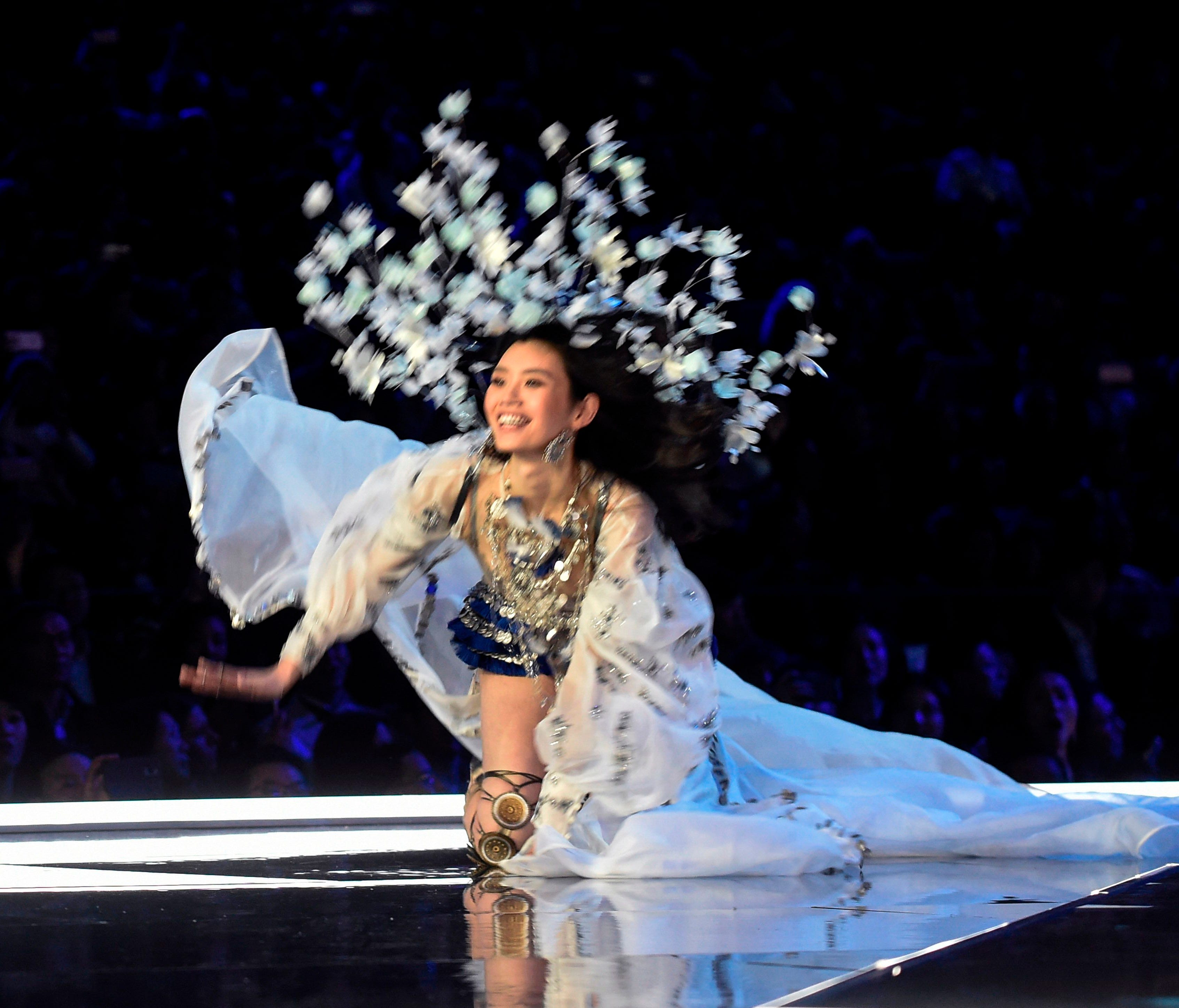 Ming Xi holds as smile as she falls on the runway.