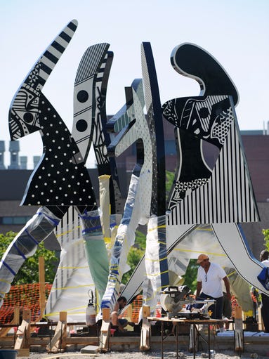 Crews work to install Charles McGee's "United We Stand"