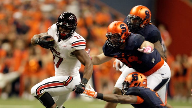 Louisville?s L.J. Scott, left, gets past Syracuse?s Ryan Sloan, top right, Robert Welsh, right center, and Durell Eskridge, bottom right, in the first quarter of an NCAA college football game in Syracuse, N.Y., Friday, Oct. 3, 2014. (AP Photo/Nick Lisi)