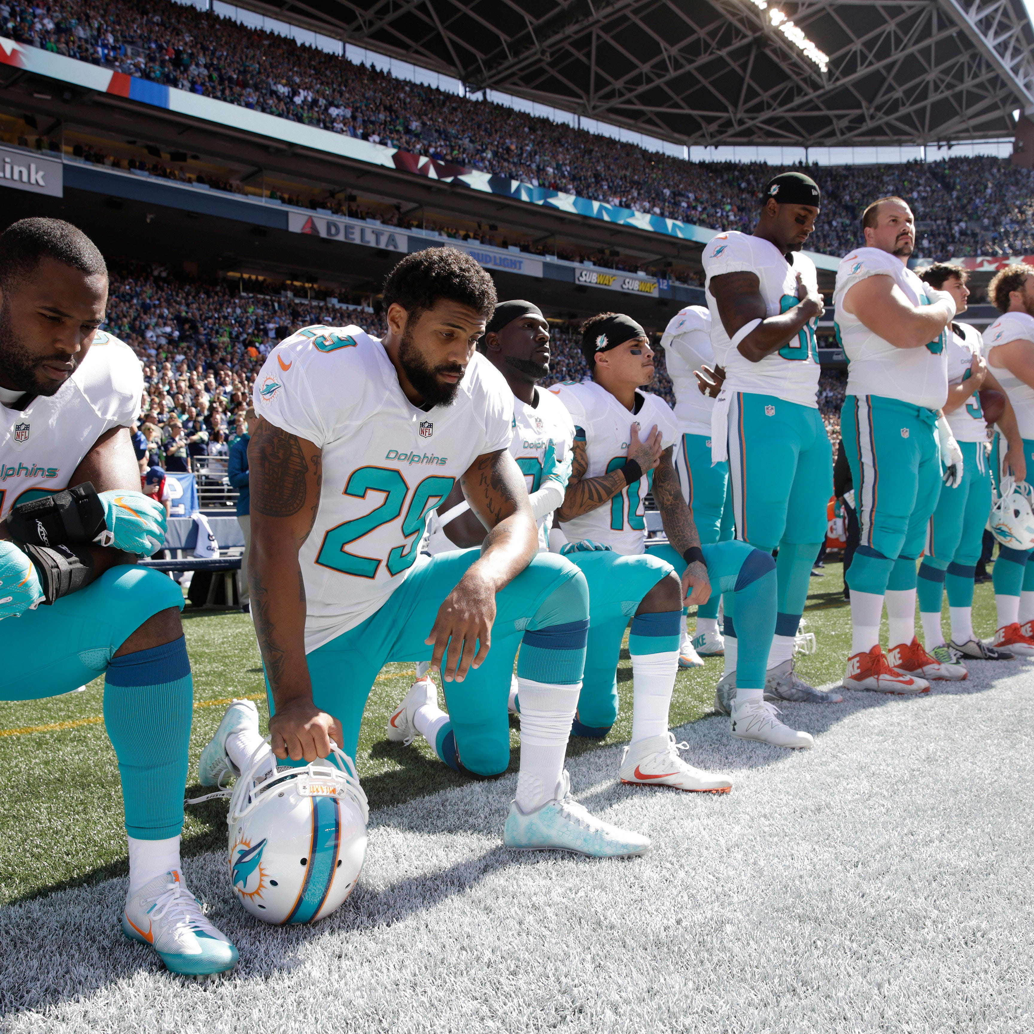 FILE - In this Sept. 11, 2017 file photo, from left, Miami Dolphins' Jelani Jenkins, Arian Foster, Michael Thomas, and Kenny Stills, kneel during the singing of the national anthem before an NFL football game against the Seattle Seahawks in Seattle. 