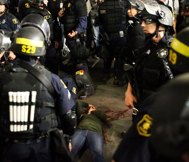 Police officers surround a fallen supporter of conservative commentator Ben Shapiro after she was knocked to the ground during a scuffle with protesters following a speech by Shapiro on Sept. 14 at the University of California, Berkeley.