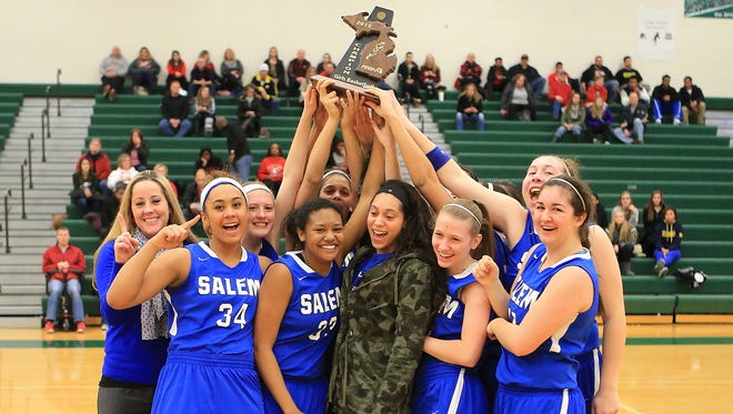 The triumphant Salem Rocks varsity girls basketball team celebrates after winning the Class A district title Friday night at Novi.
