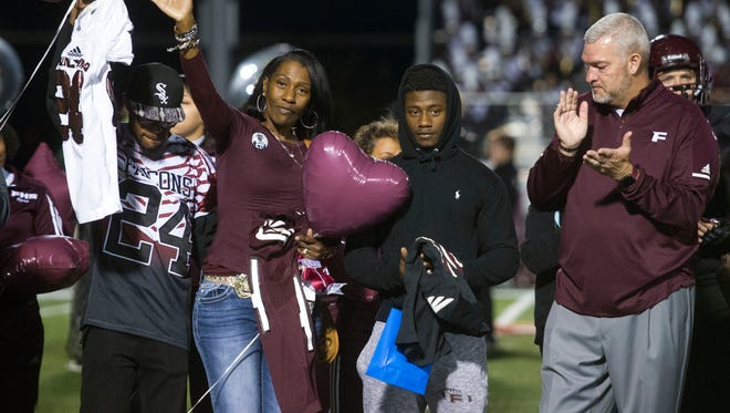 Zenobia Dobson waves to the crowd with her sons, Markastin, left, and Zack at Fulton on Friday, Oct. 27, 2017. At right is Fulton head coach Rob Black. Fulton retired Zaevion Dobson's jersey in a ceremony before the game against Oak Ridge.