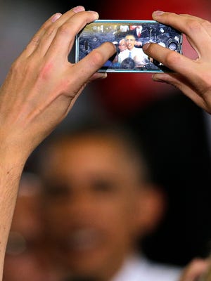 An audience member takes a snapshot of President Obama during a campaign rally for  Rep. Mike Michaud, the Maine Democratic gubernatorial candidate, in Portland.