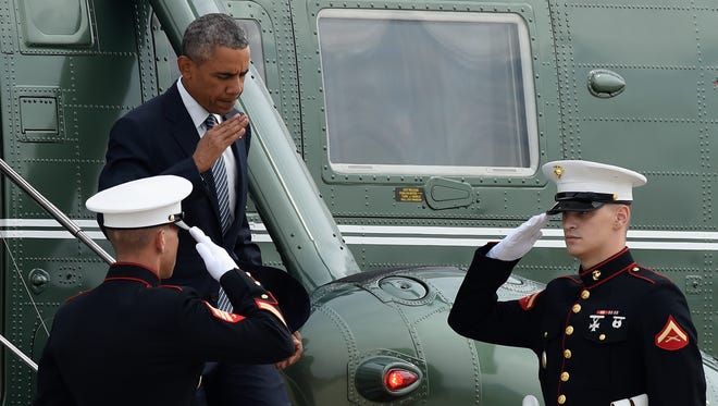 President Obama returns a salute as he walks off of Marine One to head to Air Force One at Andrews Air Force Base in Maryland Monday. Obama is traveling on a three-day trip to Alaska.