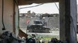 An Iraqi forces vehicle drives past a damaged building