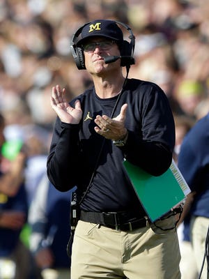 Michigan head coach Jim Harbaugh claps after a touchdown against the Purdue during the first half.