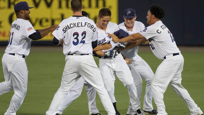 Teammates swarm Jeff Gelalich (14) after he got a walk-off hit in the bottom of the 7th inning to win 3 - 2 during the Mobile BayBears vs. Blue Wahoos baseball game one of a double header at Blue Wahoos Stadium in Pensacola, FL on Thursday, June 16, 2016.