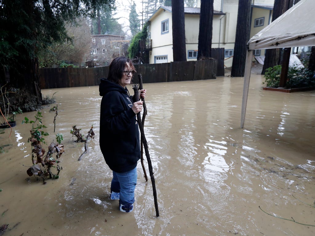 Linda Forbes walks in a flooded property as she checks on a relative living in the neighborhood in Felton, Calif. Flash flood watches are in place for parts of Northern California down through the Central Coast as heavy rains swamp roads and threaten