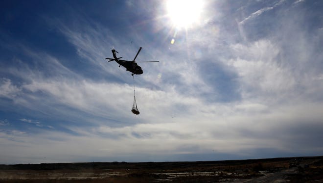 A Black Hawk helicopter on Oct. 29 carries a piece of a Pentaceratops to waiting members of the the New Mexico National Guard's 1116th Transportation Company in the Bisti/De-Na-Zin Wilderness south of Farmington.