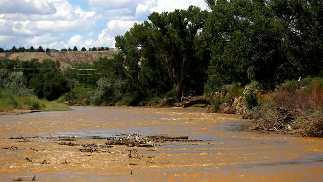 The Animas River flows near its confluence with the San Juan River in Farmington on Aug. 8, 2015, shortly after the Gold King Mine spill released millions of gallons of wastewater into the water.