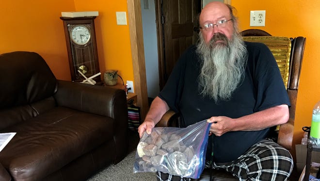 Robert Degriselles holds a bag of rocks he collected from his yard earlier this month. They were thrown by his neighbor, he said.