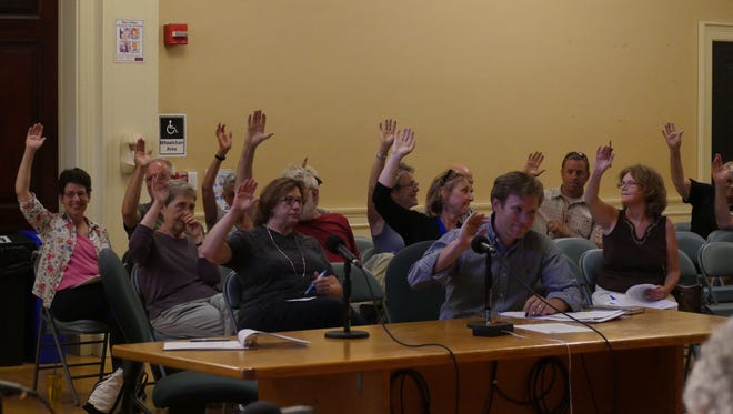 Attendees raise their hands at a Development Review Board hearing indicating they want to speak. Many who attended live near a proposed development project, and voiced their opposition to the project.