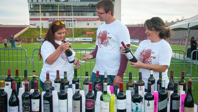 NMSU School of Hotel, Restaurant and Tourism Management students Alex Yebra, left, Austin Keyser and Carla Anaya examine the wines they’re offering during the annual beer and wine festival Novembrew at Aggie Memorial Stadium.