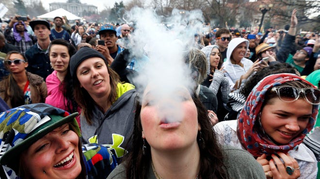 In this April 2014 file photo, partygoers dance and smoke pot on the first of two days at the annual 4/20 marijuana festival in Denver.