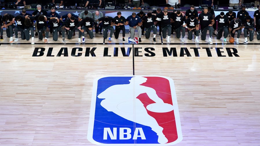 July 30, 2020; Lake Buena Vista, USA; Members of the New Orleans Pelicans and Utah Jazz kneel together around the Black Lives Matter logo on the court during the national anthem before the start of an NBA basketball game.  Mandatory Credit: Ashley Landis/Pool Photo via USA TODAY Sports
