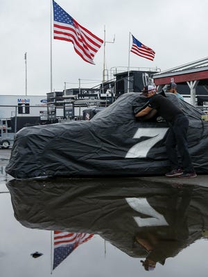 Crew members for Korbin Forrister push the covered (7) truck near the garages after the NASCAR Truck Series race scheduled for Saturday afternoon was postponed to Sunday morning due to weather at Pocono Raceway, in Long Pond, Pa.